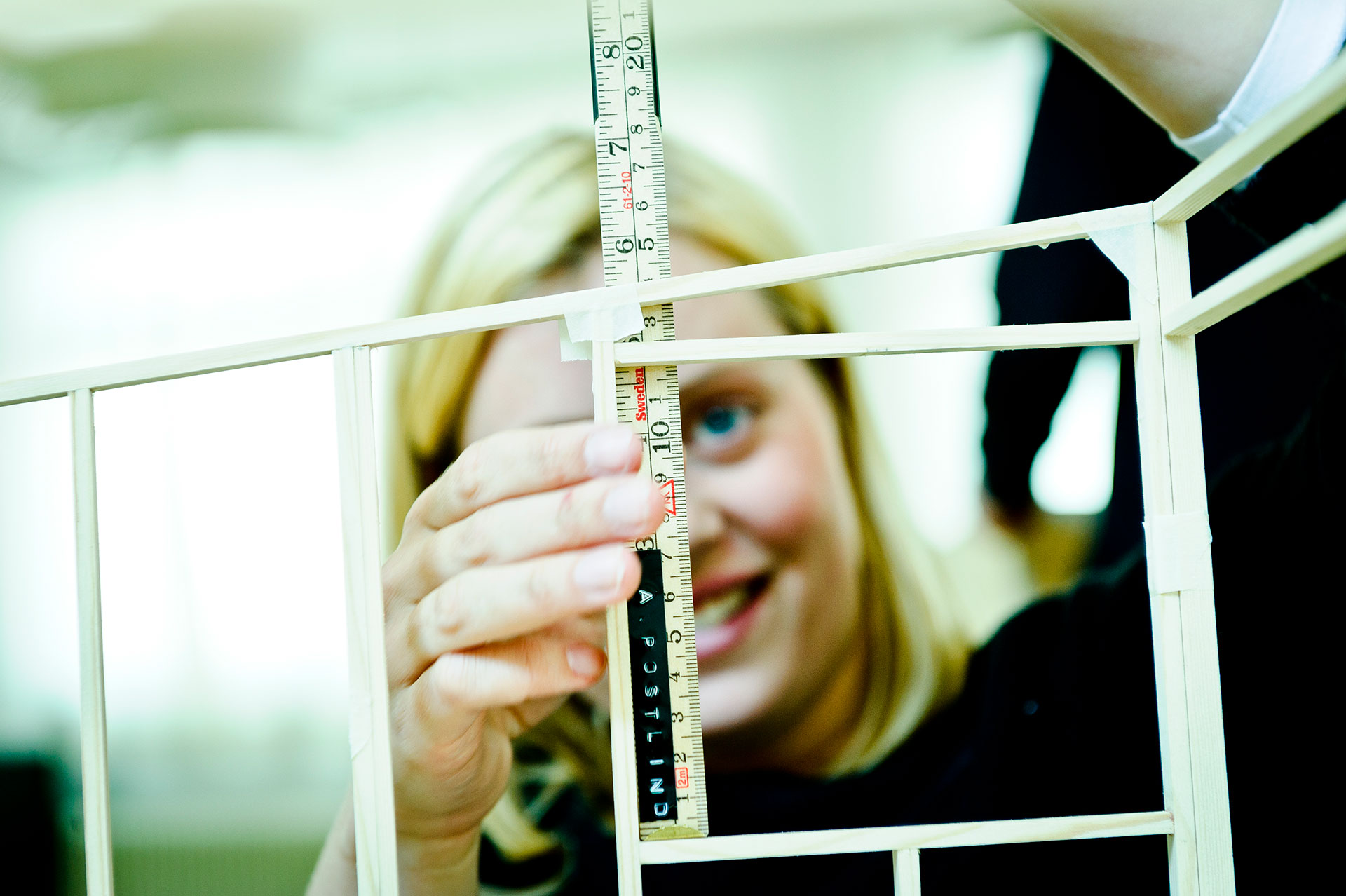 Student holding a tranparent ruler against a scale-model. Photo.